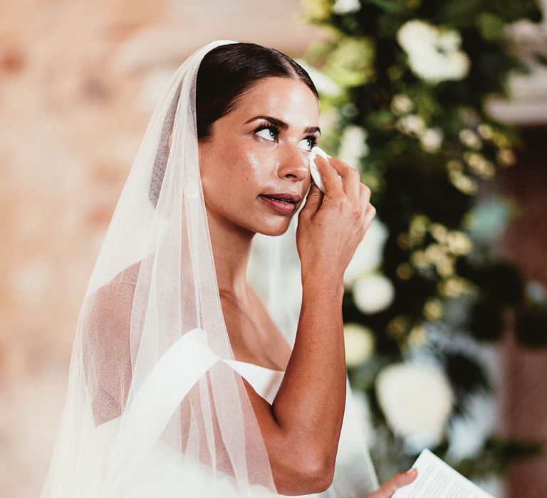 Bride becomes emotional during wedding ceremony as she dries her eyes with tissue