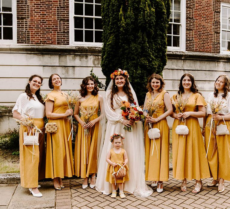 Bride stands with her bridal party who wear custom made yellow wedding gowns in different styles