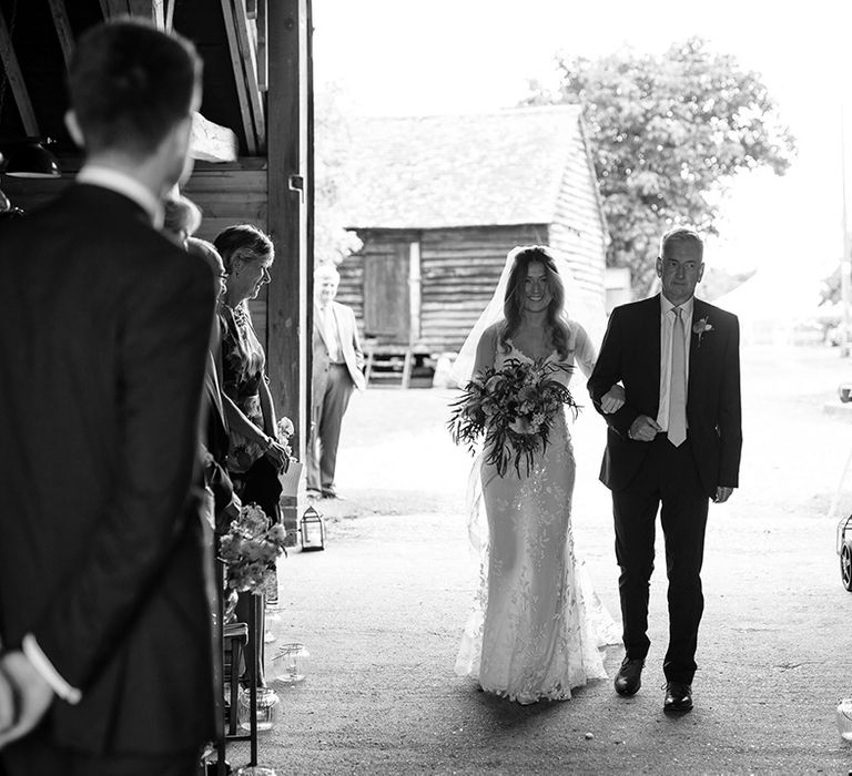 Bride walks down the aisle at barn ceremony