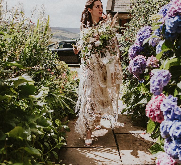 Bride arrives on wedding day holding large floral bouquet