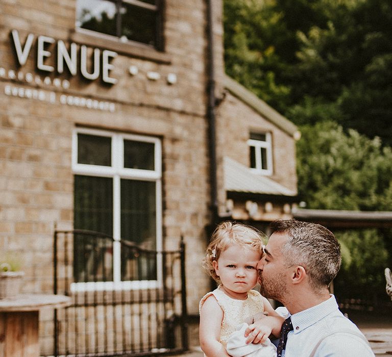 Wedding guest kisses the cheek of his daughter 