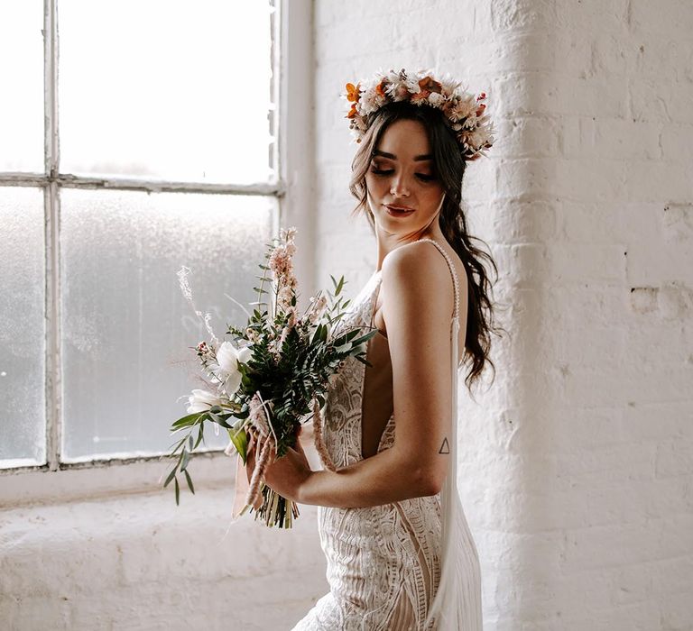 Boho bride in a lace and fringe wedding dress with dried flower headband 