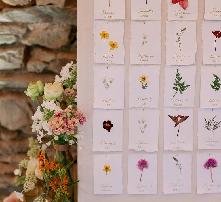 Pressed wildflower cards personalised with guests' names for seating chart 