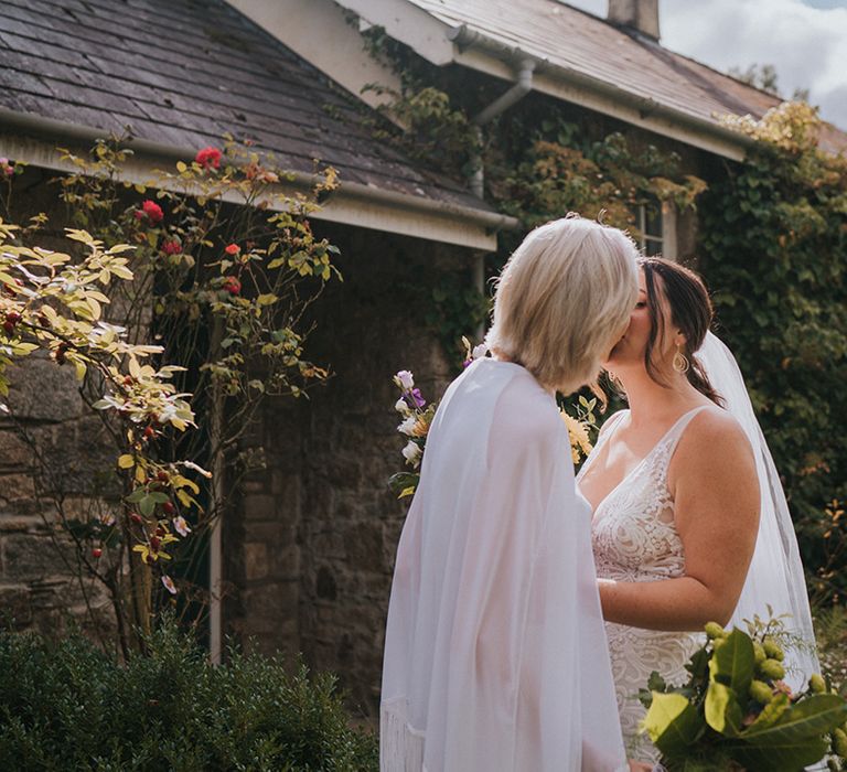 Brides share a kiss on their sunny September wedding day at Colehayes Park