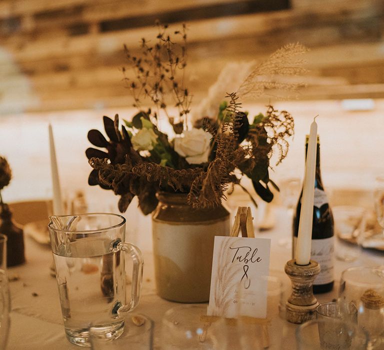 Small assortment of light and dark flowers for table settings with card with table numbers on small wooden stand