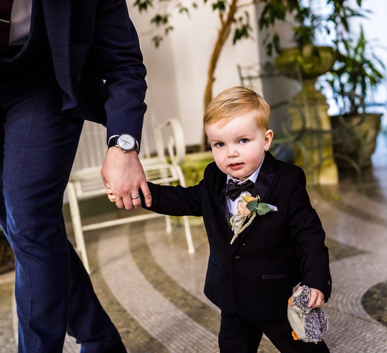 Young wedding guest in black tie suit with stuffed toy