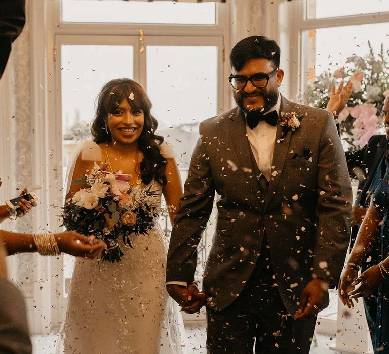 Bride in traditional white wedding dress with mixed flowers bouquet and groom in dark grey suit with black bowtie 