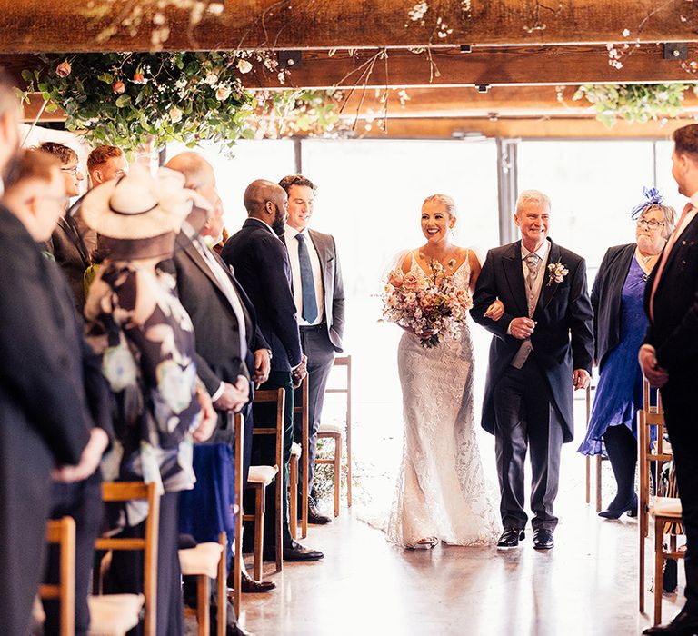 Father of the bride in traditional and classic morning suit walks the bride down the aisle 