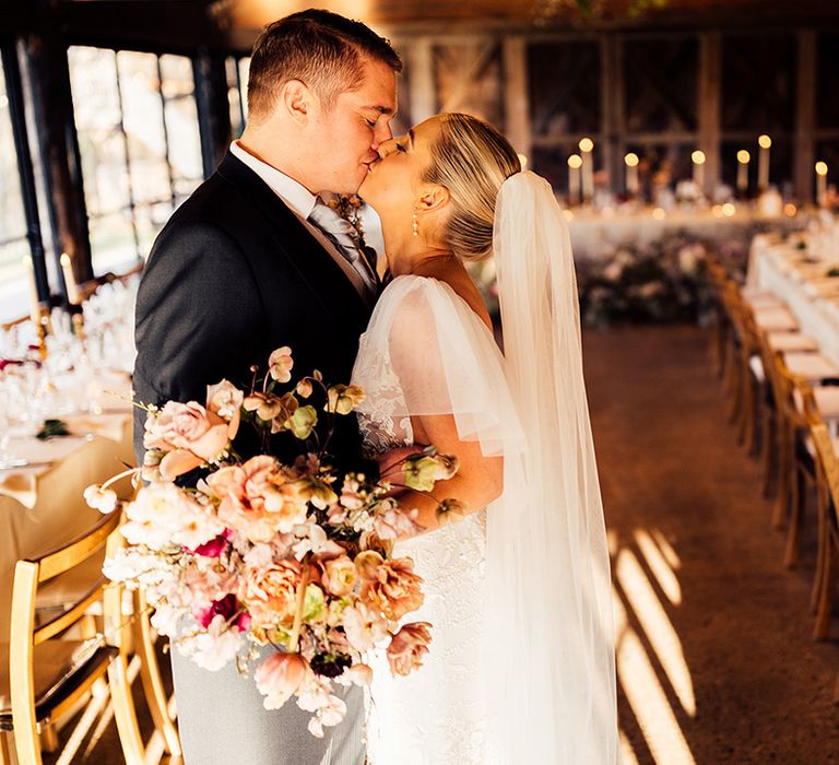 Bride and groom kiss in the reception room at Dewsall Court decorated very traditionally and classically 