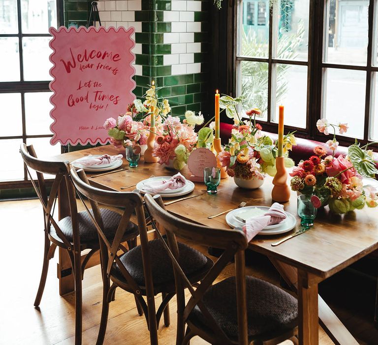 Pink and red wedding welcome sign and tablescape with zesty yellow, green and pink flowers, ombre candles and on the day wedding stationery at Singer Tavern 