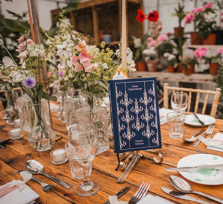 Classic book sits on wooden table surrounded by colourful florals 