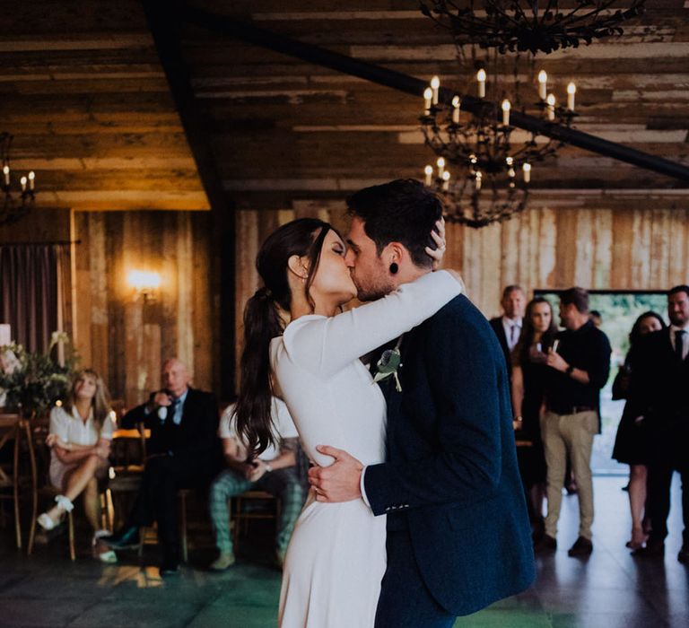 Bride and groom kiss during their first dance together 