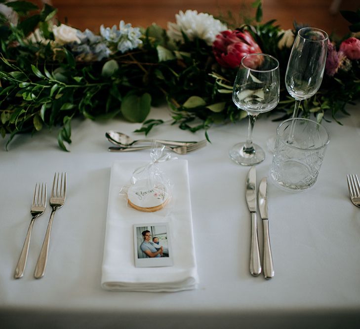 White napkins complete with personalised biscuit favours and large bouquets to the middle of tables