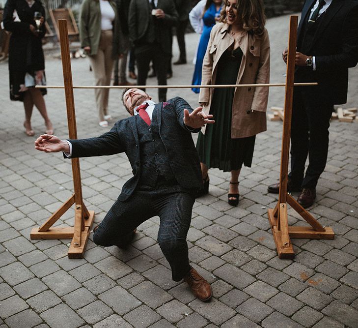 Man does the limbo for outdoor wedding games 