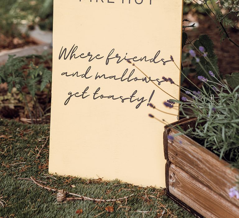 Pale yellow arch wedge sign for the fire pit for guests to have s'mores 