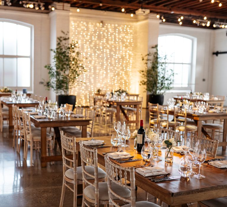 Rustic styled Trinity Buoy Wharf with wooden tables and fairy light canopy behind sweetheart table 