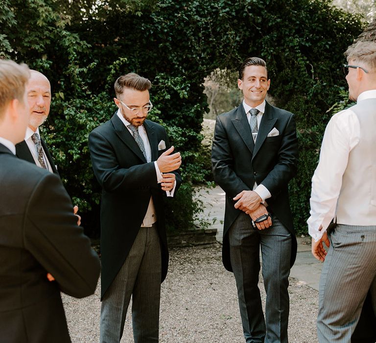 Groom stands outside with the groomsmen as they all get ready together in the morning for the day 