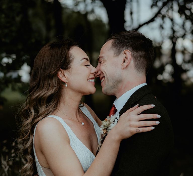 The bride and groom lean in for a kiss as they pose for couple portraits on their wedding day 