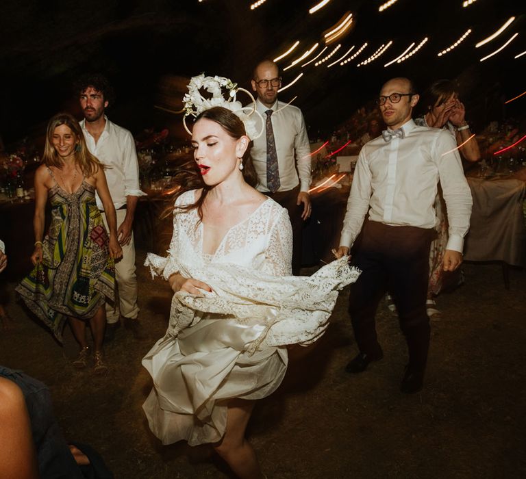 Bride in lace wedding dress, pearl earrings and bridal crown dances at wedding reception in Italy