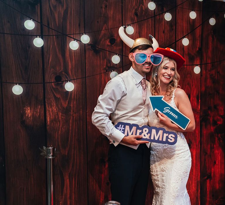 The bride and groom pose together with silly and fun props for their photo booth wedding entertainment 