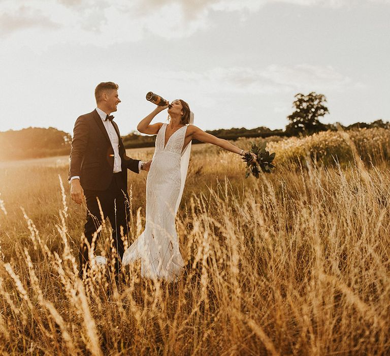 Champagne popping moment for the bride and groom during golden hour 