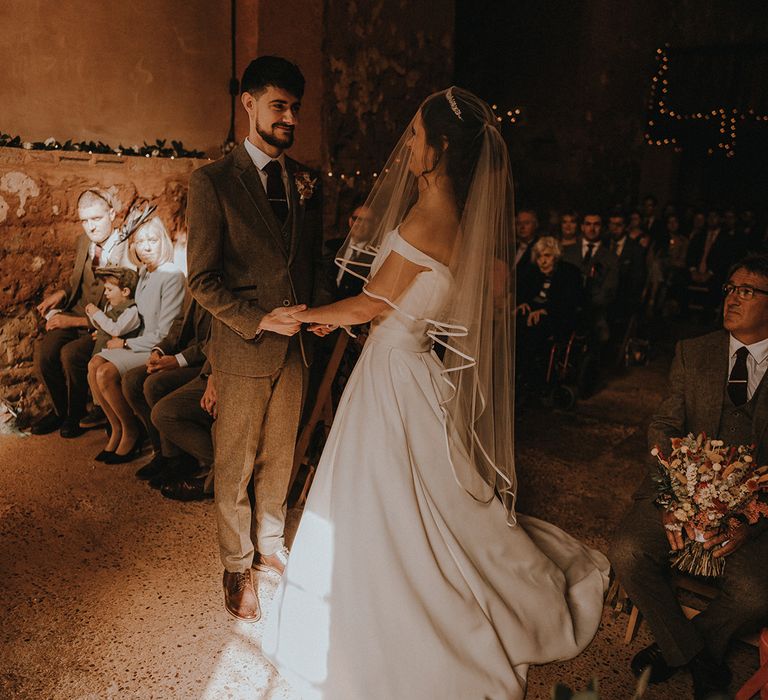 Bride wearing tiara and veil holds hands with the groom for the civil wedding ceremony in Devonshire 