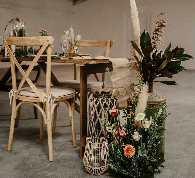 Rustic boho wedding tablescape with rattan vases with foliage, garden rose, pampas grass and dried flower boho flower arrangements at The Barn at Avington