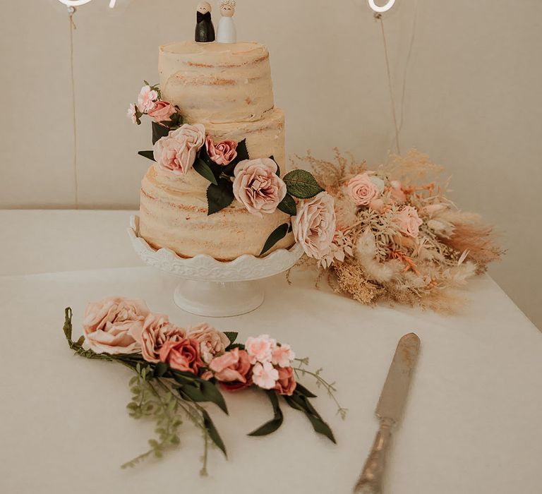 Semi-rustic three tier wedding cake with cute cake topper with pink peonies and rose cake decoration with personalised white neon sign 