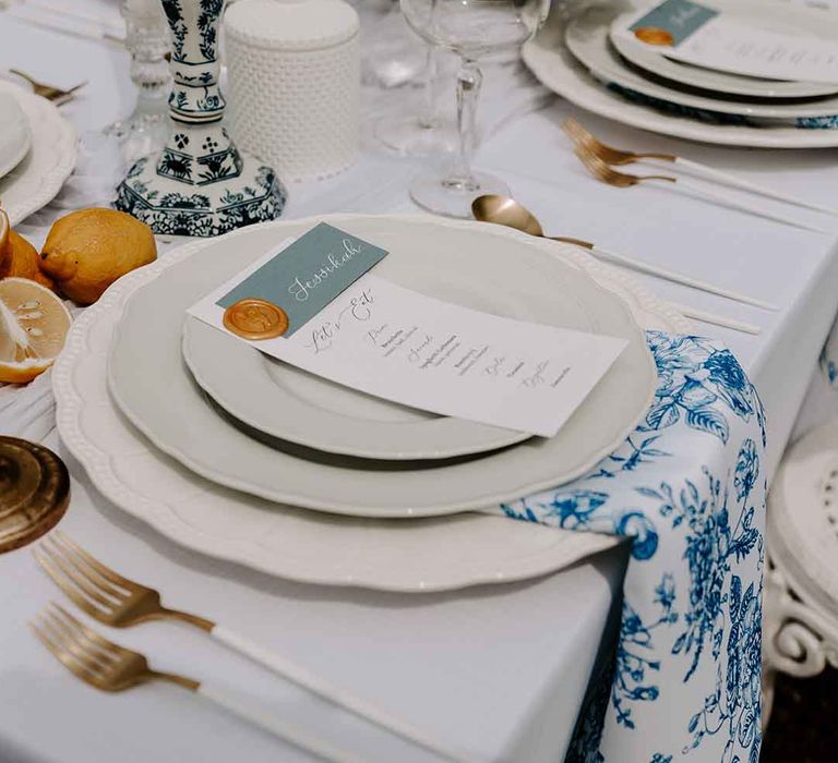 place setting with blue and white napkin and candlestick holders, intricate tableware, white cutlery and lemon decor