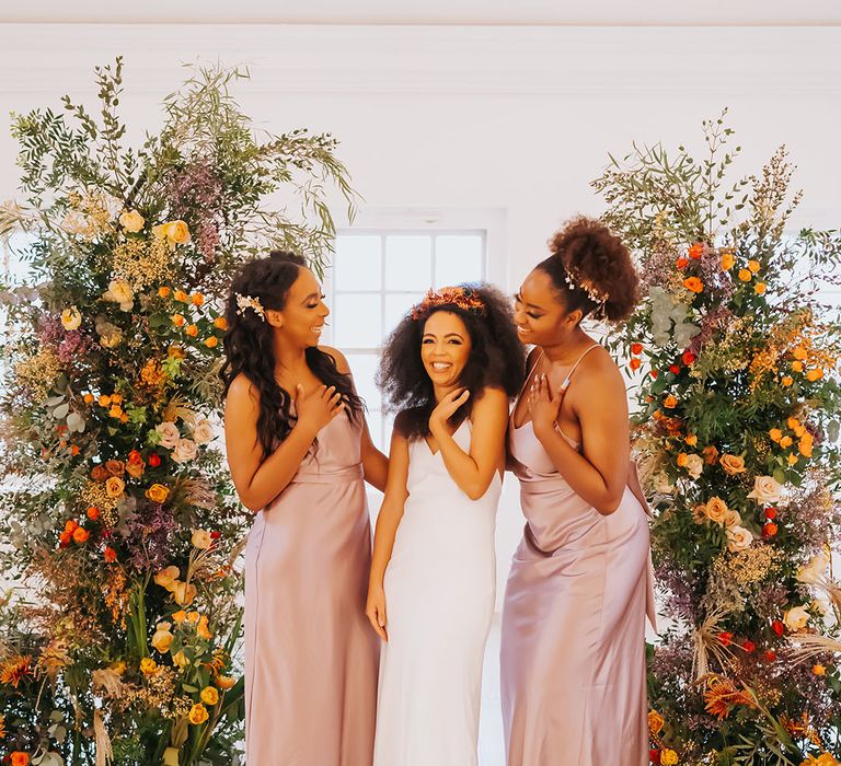 Bridesmaids in pink satin dresses with the bride in a similar style slip dress 