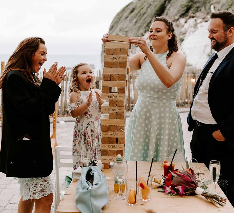 Wedding guests playing large wedding jenga outside reception room at Tunnels Beaches wedding venue 