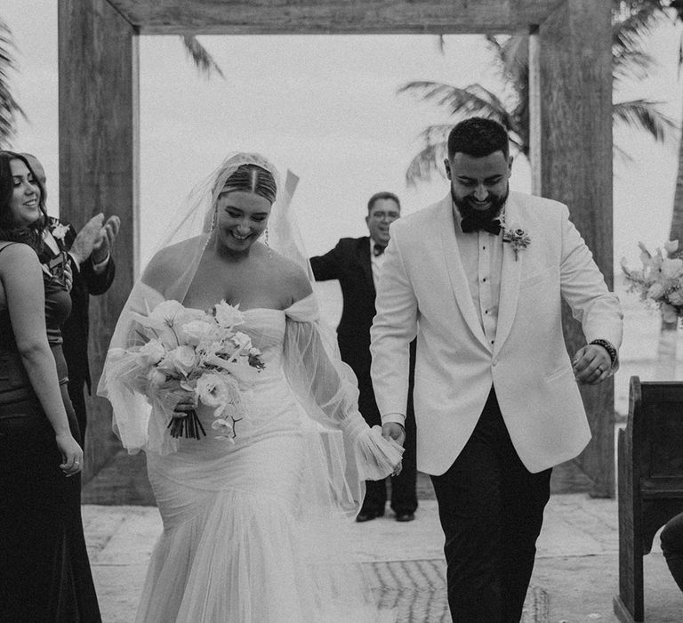 bride in a strapless wedding dress and groom in a tuxedo descending up the aisle at blue venado beach wedding ceremony 