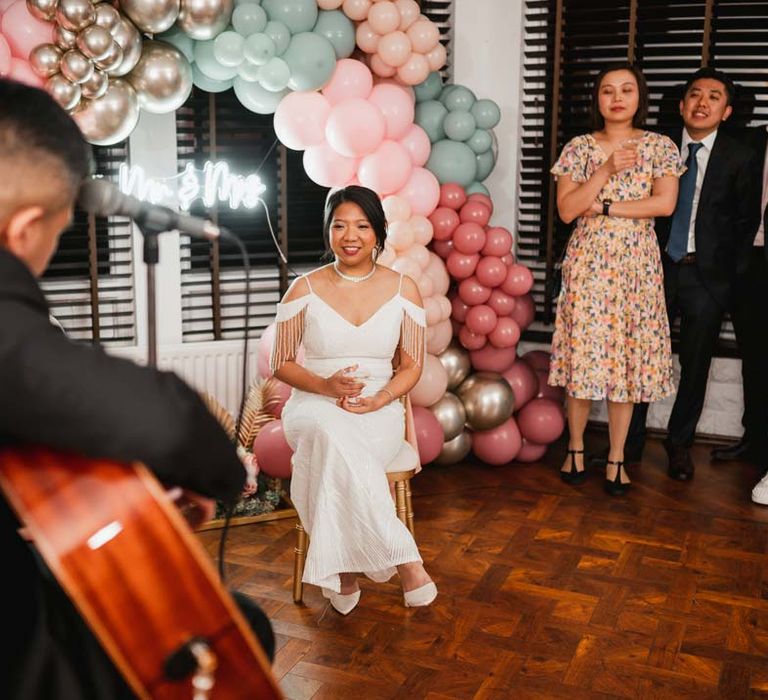 Groom playing the guitar for bride in white beaded and sequined slip wedding dress