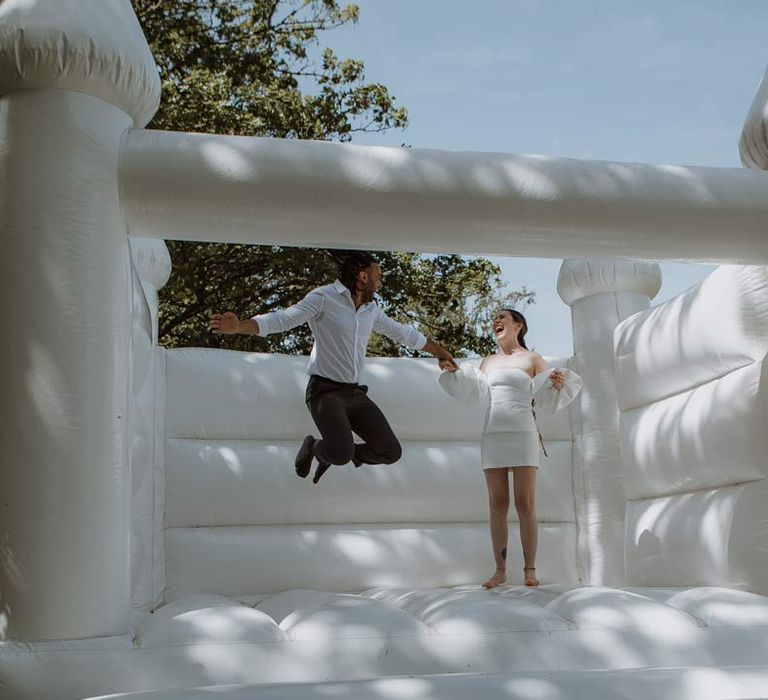 Bride and groom jumping on outdoor wedding bouncy castle at The Old Rectory Berkshire 