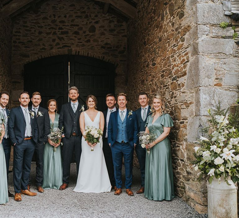 Wedding party with the groomsmen in dark navy suits and bridesmaid in light green satin bridesmaid dresses 