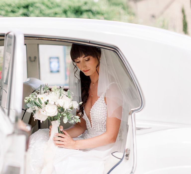 bride in an appliqué wedding dress and elbow length veil holding a classic white rose wedding bouquet 