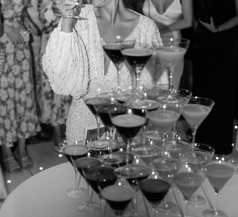 Bride in beaded wedding reception dress with balloon sleeves at cocktail tower with espresso martinis and pornstar martinis 