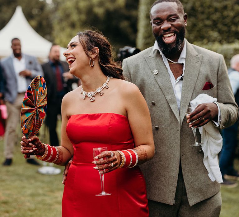 Bride in stunning bright red strapless reception dress with groom at the outdoor wedding performance 