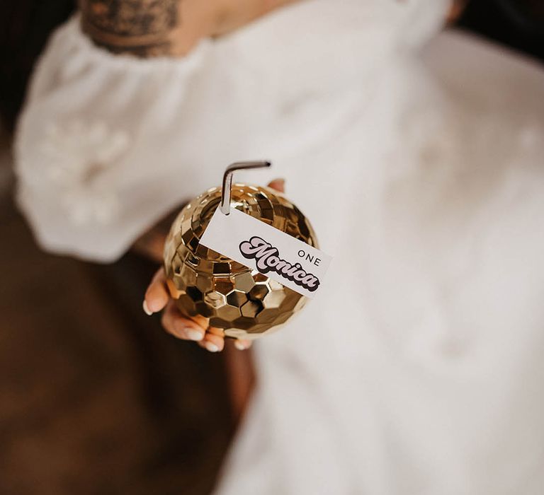 Bride drinking from a gold disco cup and straw with place name card and seat number  