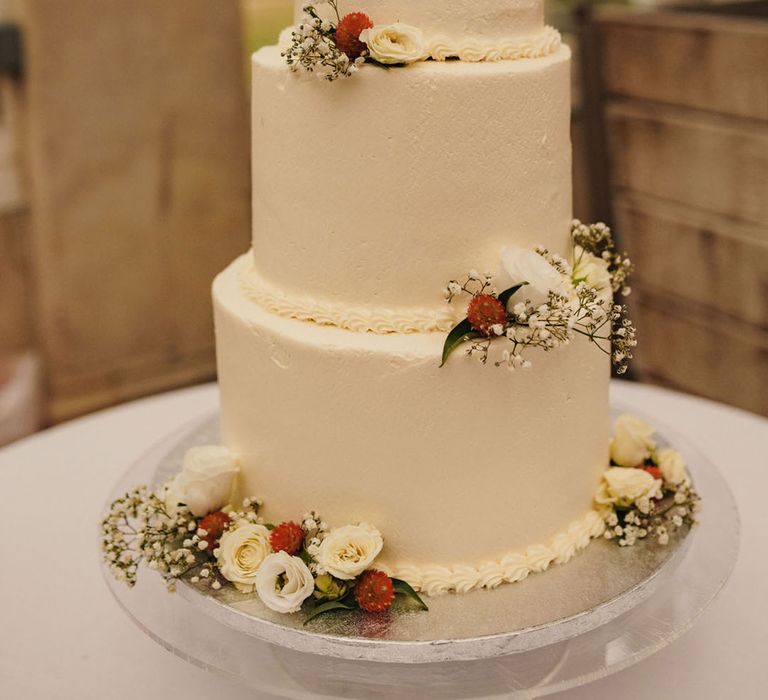 Three tier white buttercream wedding cake decorated with neutral flowers 