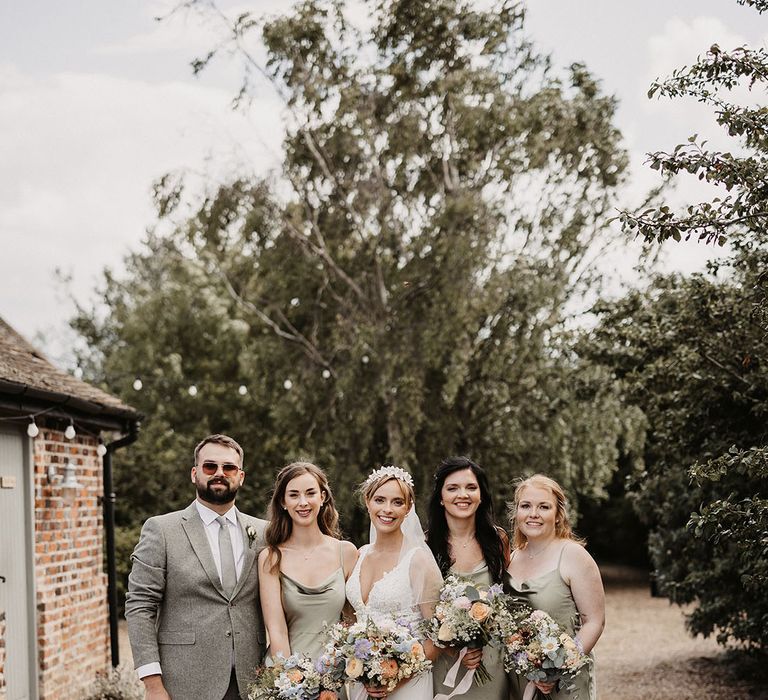 Bridal party wearing sage green satin bridesmaid dresses with pet dog wearing a wedding outfit 