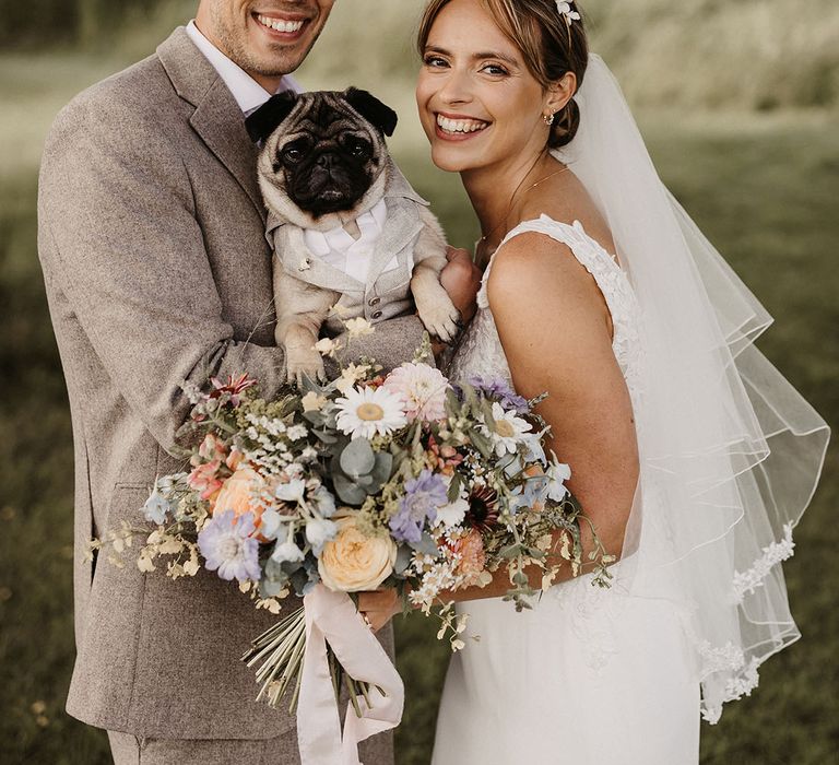 Cute couple portrait of the bride and groom with their pet dog in a dog wedding outfit 