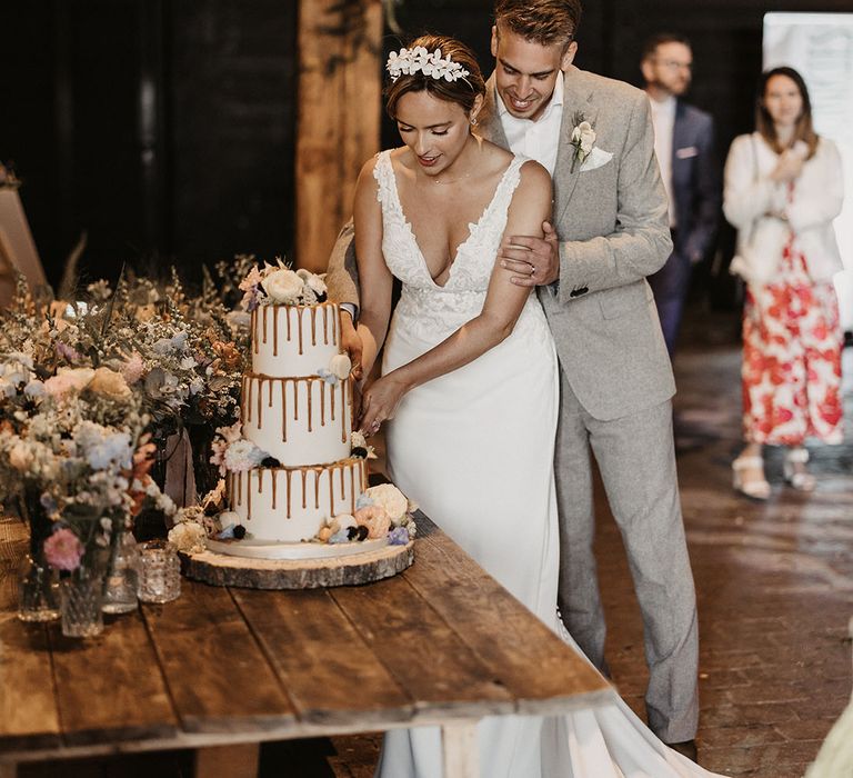 The bride and groom cut the drip wedding cake 