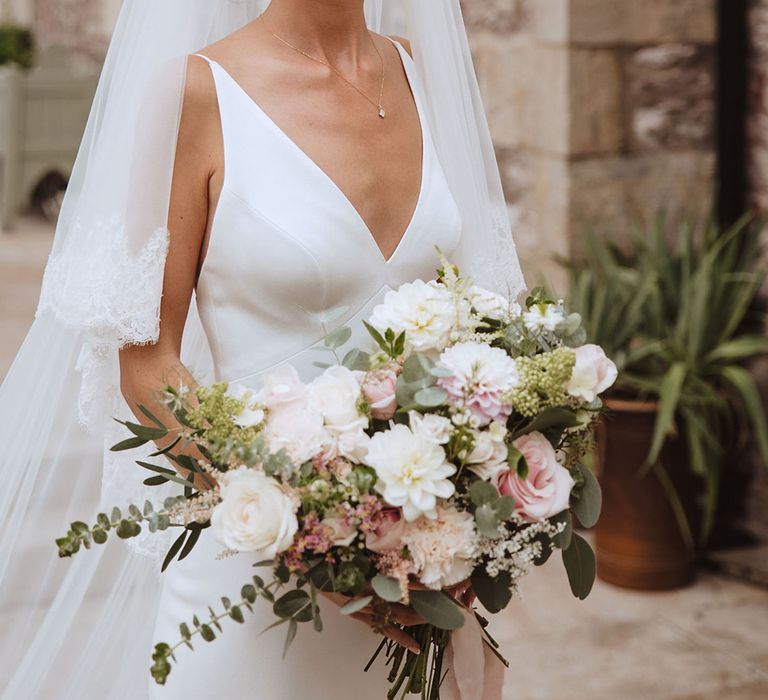 Bride wearing satin plunging wedding dress holding blush pink and white wedding bouquet 