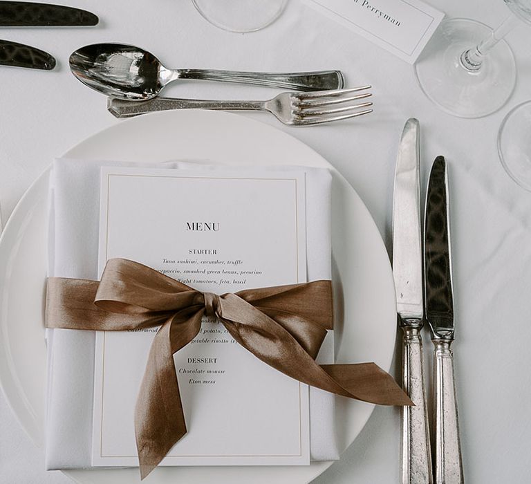 White classic wedding place setting with wedding menu decorated with brown satin bow decoration 