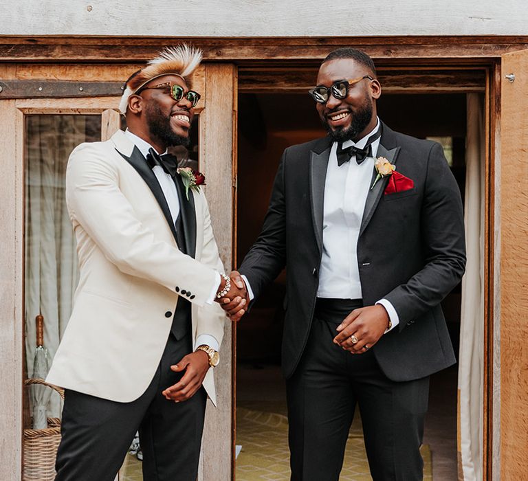 Groom in white tuxedo with groomsman in black tie for classic style wedding 