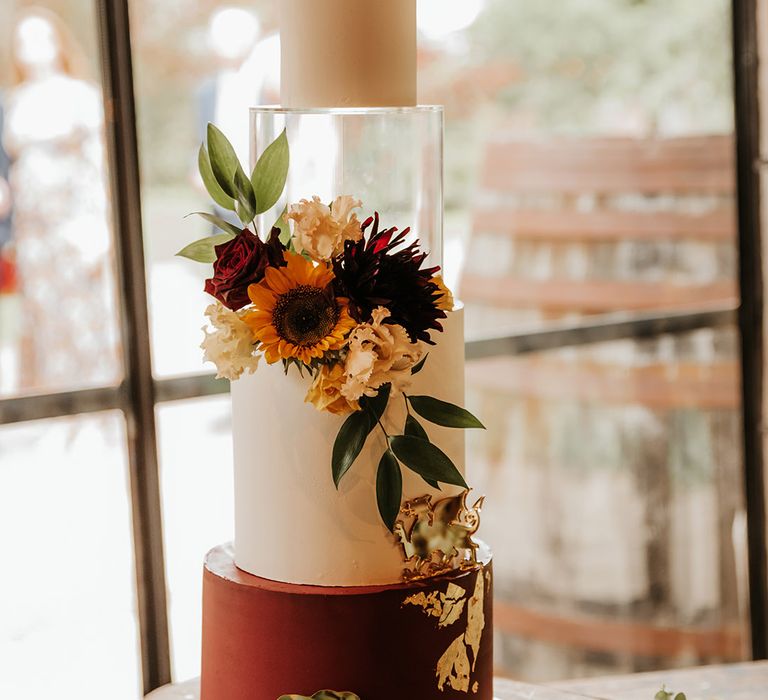 Four tier autumnal wedding cake with red roses and sunflowers with spacer layer for modern look 