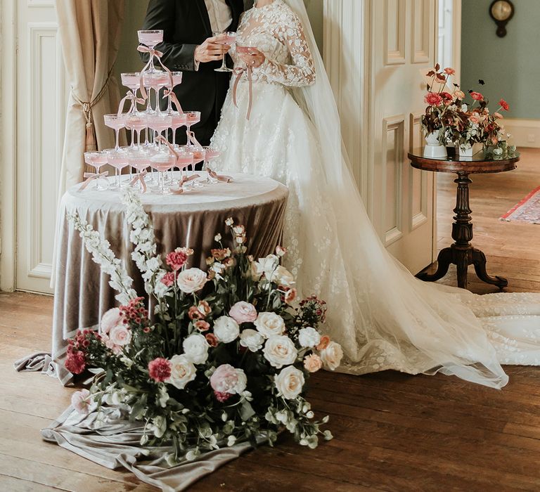 Bride and groom posing next to pink champagne tower wedding decor 