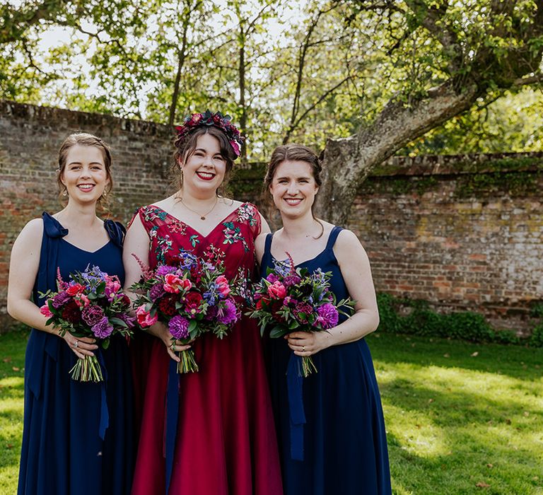 Bridal party wearing navy blue bridesmaid dresses with the bride in a red wedding dress with delicate embroidery detail 