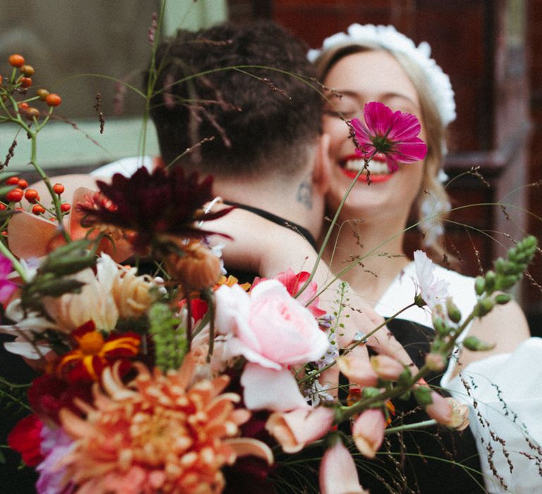 Bride and groom share a hug with a close up on the assorted wedding bouquet